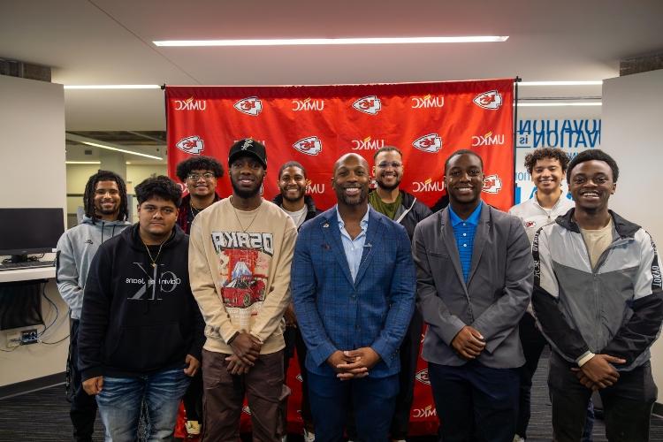 UMKC Men of Color Academy students pose for a group photo with Ramzee Robinson of the Kansas City Chiefs in front of UMKC and Chiefs backdrop